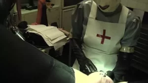 Rubberverpleegster agnes - lange grijze latex verpleegsterjurk, witte operatiekap en masker - deel 1 - pijpbeurt en prostaatmassage